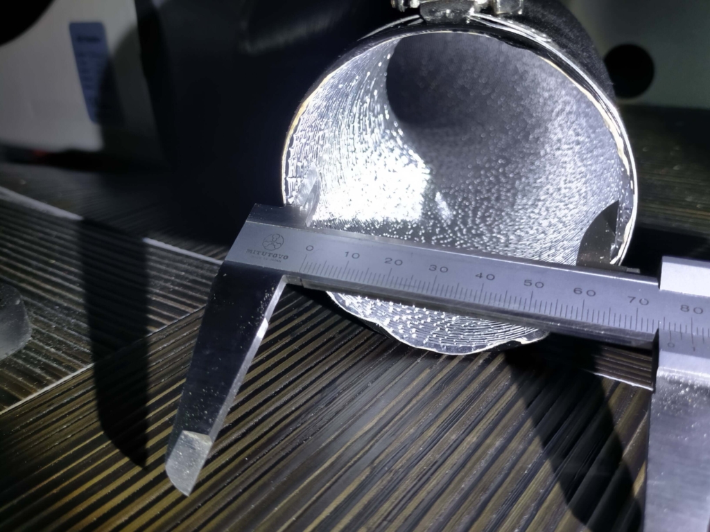 中華FFヒーター(5KW 12V)の温風ダクト内径を実測した写真。75mm径のダクトホースおよび吹き出し口グリル(BSTQC製など)の購入・交換時に必要なサイズ確認用。E-06ファンモーター動作不良やE-05オーバーヒートのトラブルシューティングにも関連する冷却・排気系部品の確認