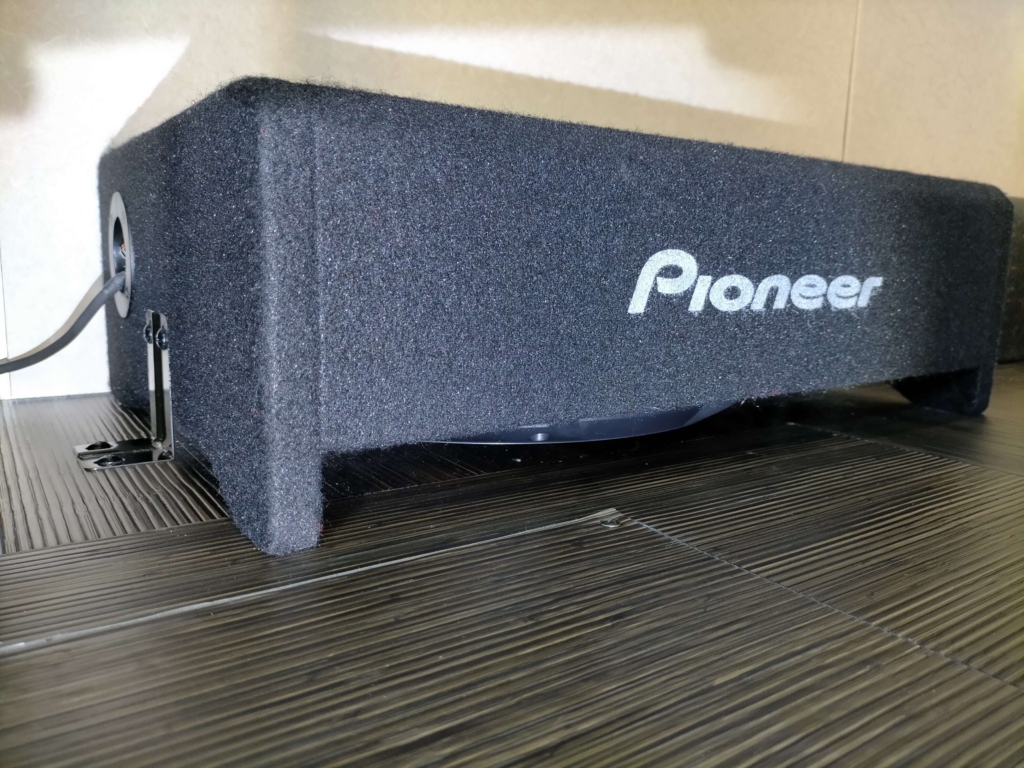 カロッツェリア TS-W3020(30cmサブウーファー)と専用薄型エンクロージャーUD-SW300Dの実車設置写真。いすゞコモ/キャラバンのような商用バンの限られたスペースにも設置可能な薄型専用ボックス。GM-D8400のChannel Bブリッジ接続(LPF 80Hz)で駆動。後継機TS-WX3030も選択可