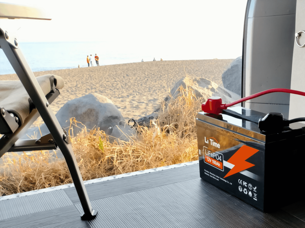 LiTime LiFePO4 12V 100Ahバッテリーをバンから降ろして海辺のアウトドアシーンで活用した様子。軽量設計で持ち運びが容易なため砂浜でのコーヒーメーカー使用など屋外電源としても活躍