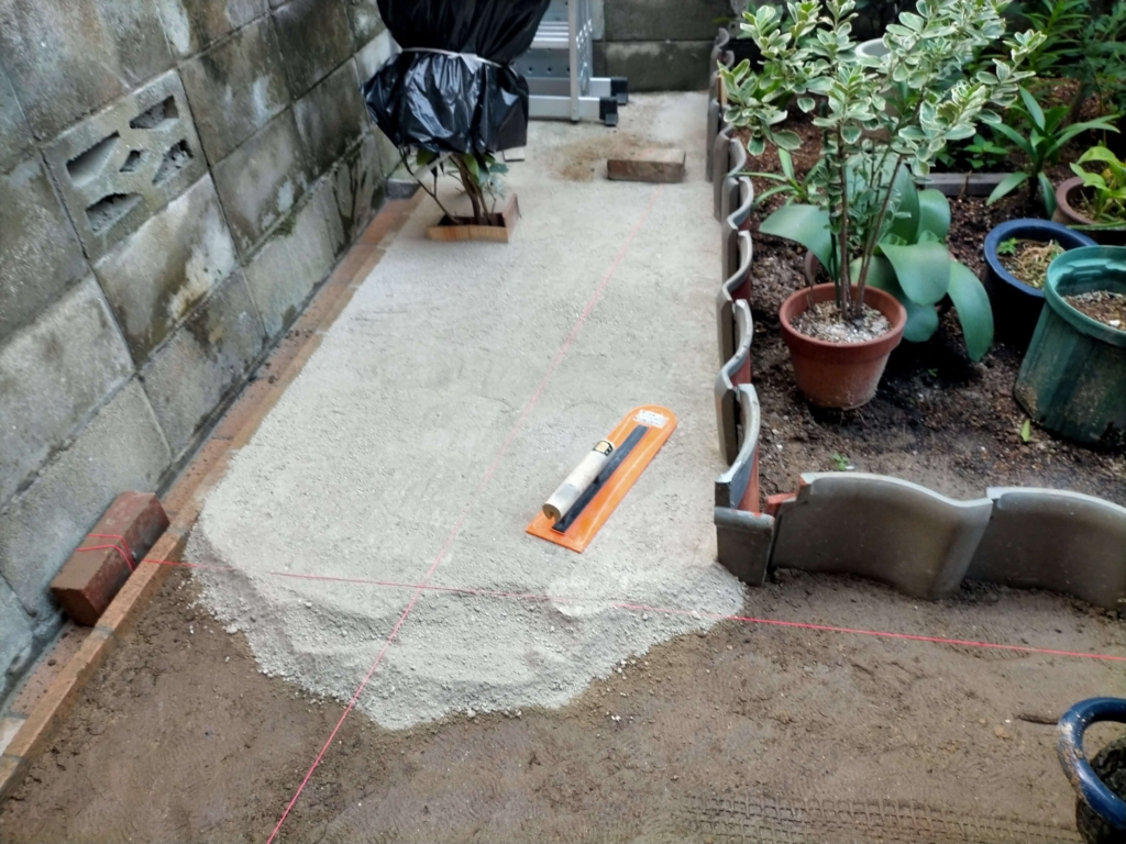 立水栓ポーラスコンクリート水受け周囲の仕上げとして固まる砂を敷き均している作業