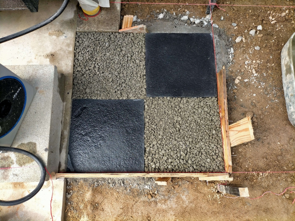 立水栓水受けエリアに濡らした地面へポーラスコンクリートを多めに盛り土間ごてで転圧しながら打設している作業