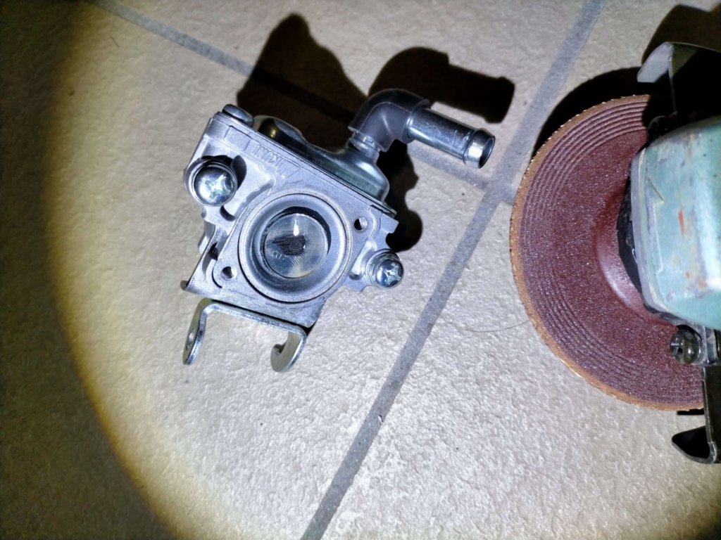 セロー250AISエアカットオフバルブの部品を分解するためにグラインダーでカシメ部分を削り取っている作業