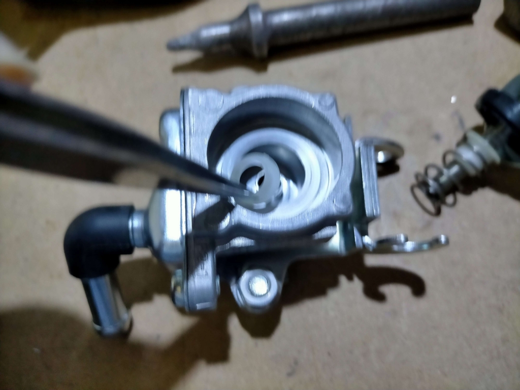 セロー250AISエアカットオフバルブのボディ内部に残った樹脂製リテーナーをマイナスドライバーでこじって取り外している作業