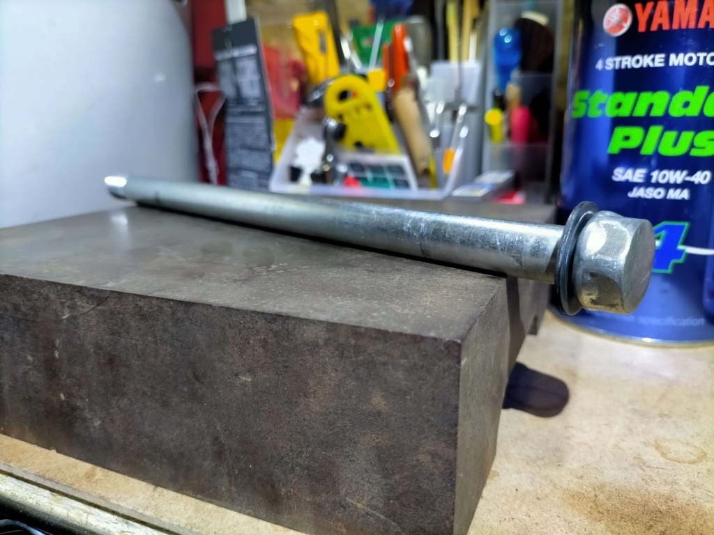 セロー250フロントホイールの組み付け前にアクスルシャフトをV字台に乗せてダイヤルゲージで曲がりを点検している作業