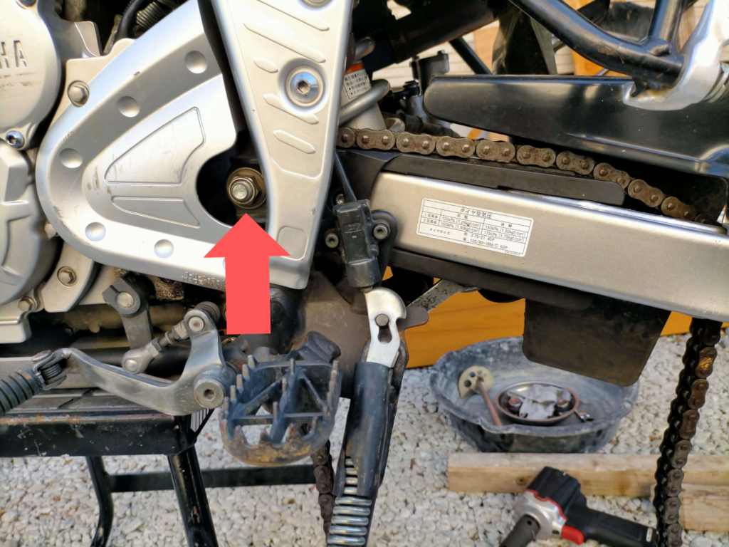 セロー250スイングアームピボットシャフトのナット位置と取り外し箇所を示した状態(ナットを外してシャフトを引き抜く手順)