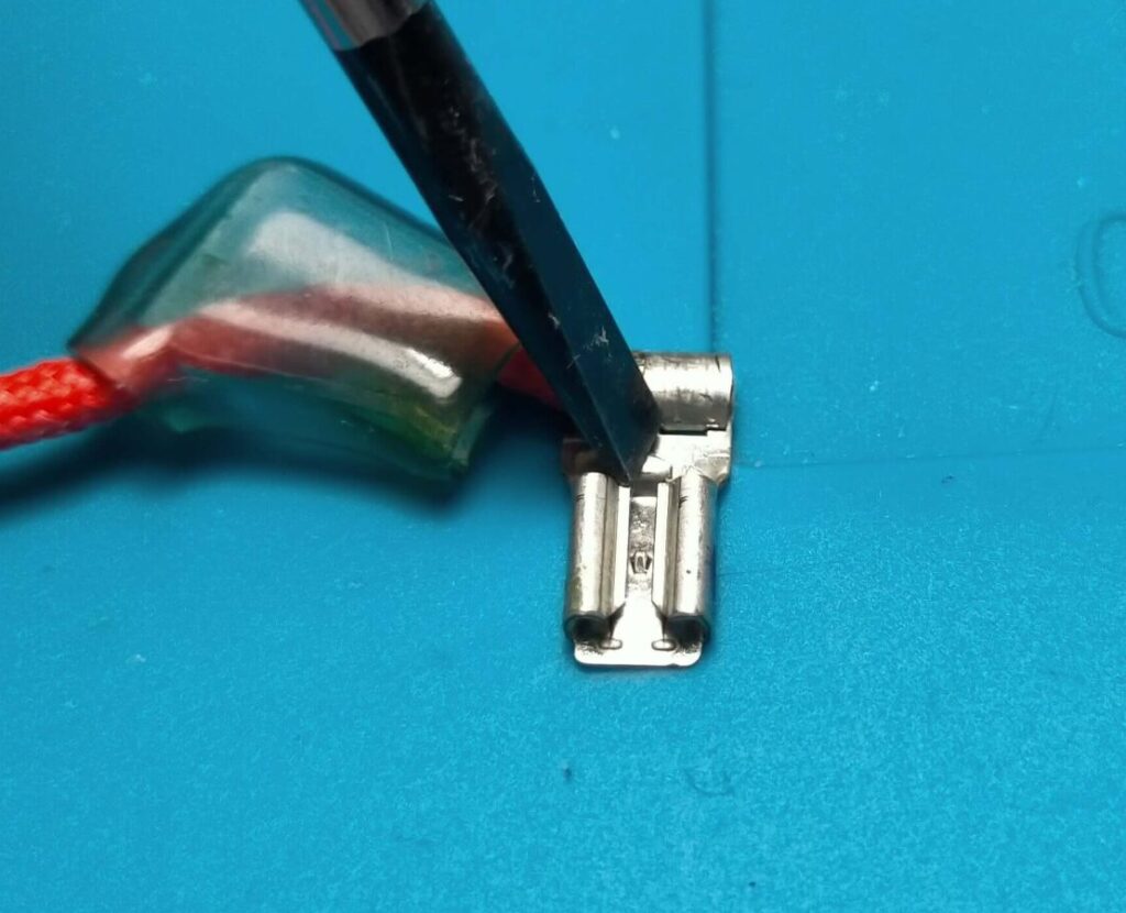 炊飯器電源コネクタのロック解除レバーをマイナスドライバーで押さえる様子の拡大図