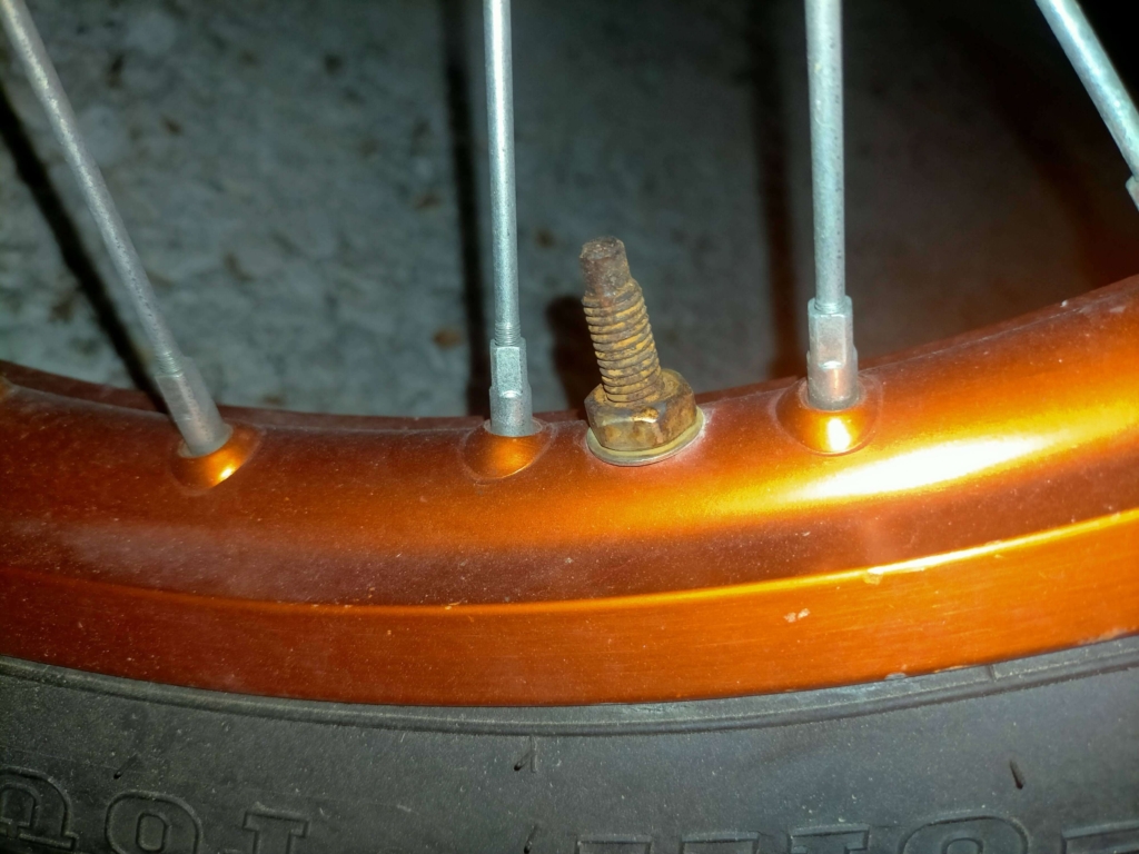 セロー250フロントホイールにDRCリムロックを取り付けて10ヶ月後の状態(ステンレスボルトに青空駐車によるサビが発生している様子)