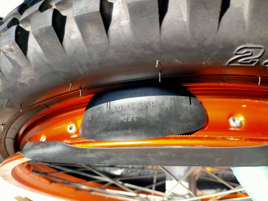 セロー250フロントリムの8mm穴にDRCビードストッパー本体を挿し込んでセットしている作業