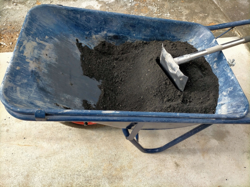 砂25kg・セメント10kg・松煙墨1.1kg・hiメトローズ10gを左官鍬で均一になるまで空練りした黒いモルタルの状態(9月29日16:00)