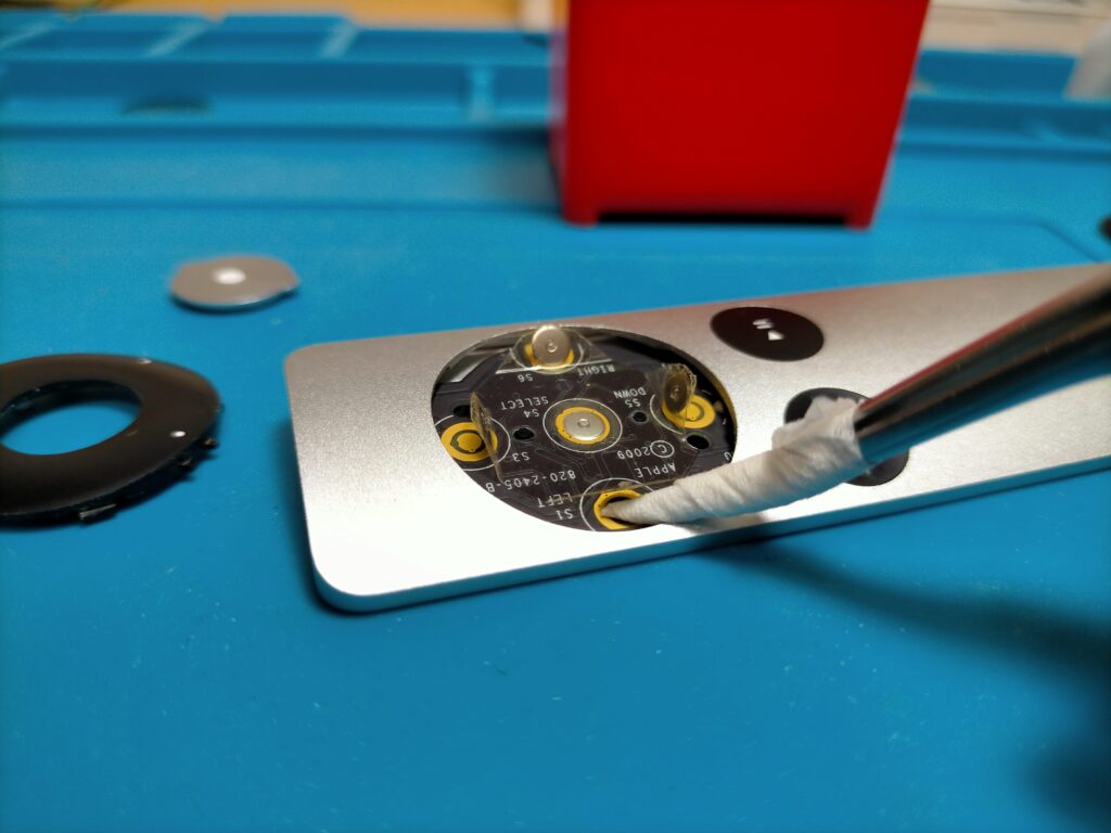 Apple Remoteの方向ボタン基板の接点テープをめくってイソプロピルアルコールで清掃している作業