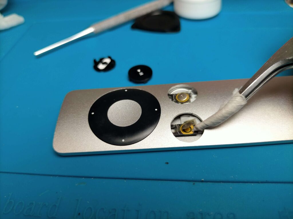 Apple RemoteのMENUボタン・再生一時停止ボタン基板の接点テープをめくってイソプロピルアルコールで両面清掃している作業