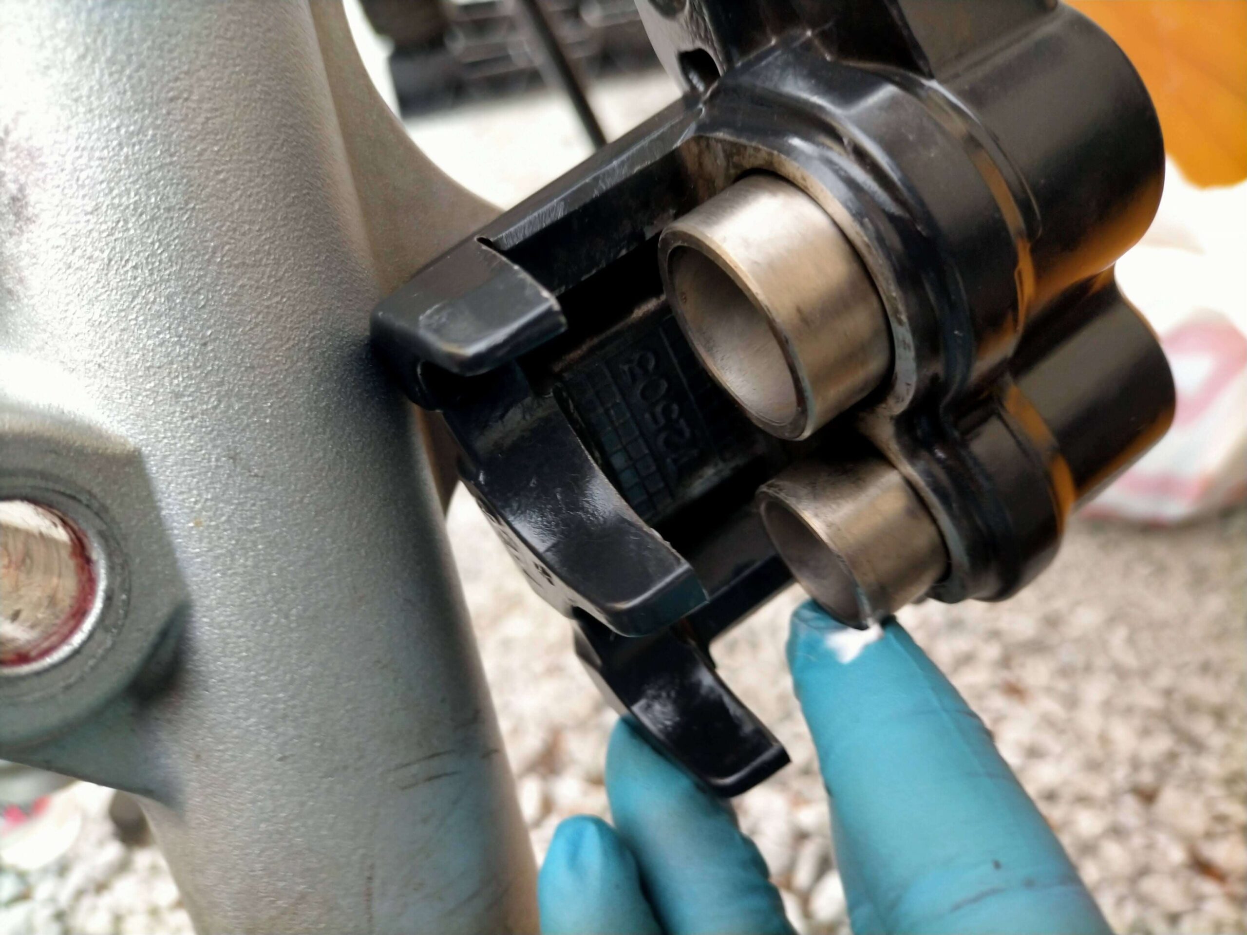 セロー250フロントブレーキキャリパーのピストン側面とダストシール部分にシリコングリスを塗布している作業