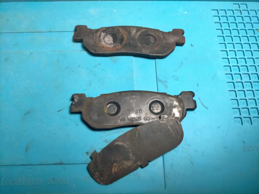 セロー250純正フロントブレーキパッドのピストン非接触側裏面に装着された純正シム（5XT-25828-00）の状態