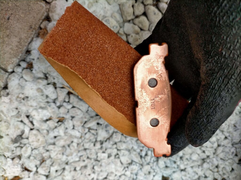 セロー250フロントブレーキパッド（デイトナ ゴールデンパッドX）の角を60番ヤスリで面取りして初期馴染みと鳴き止め加工をしている作業