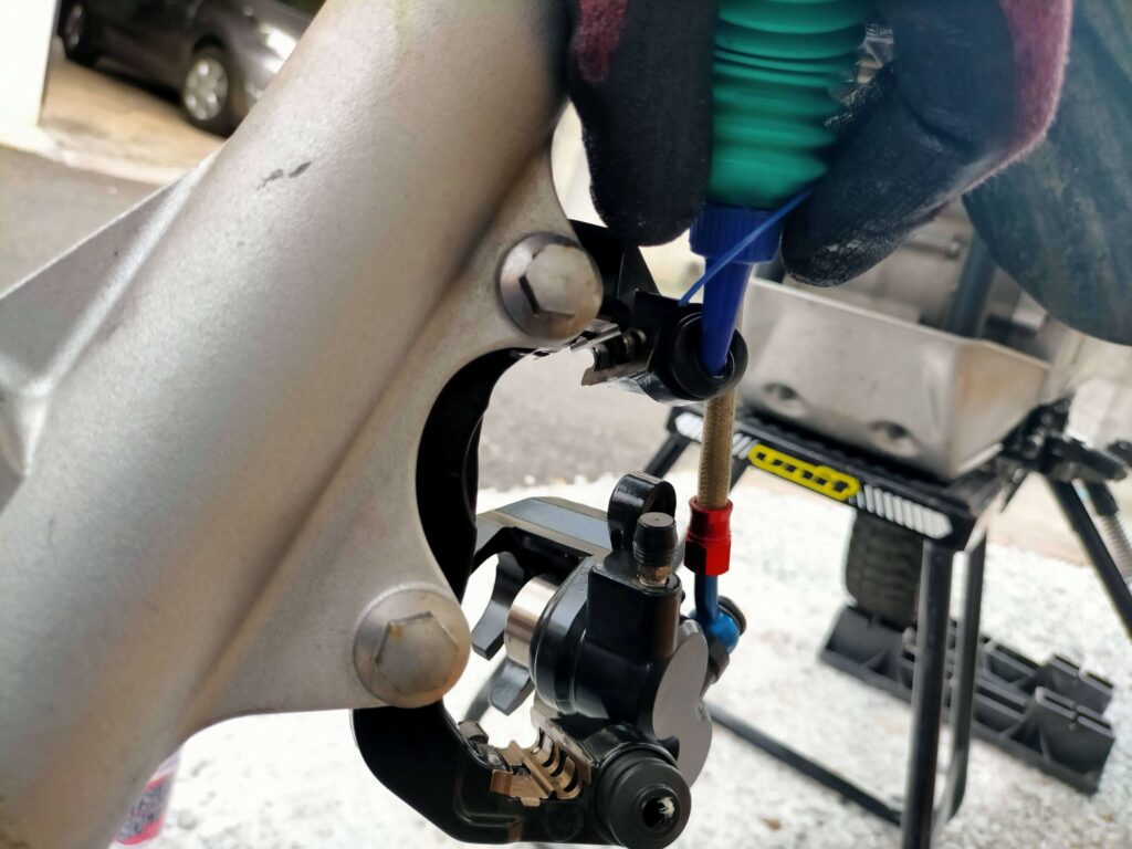 セロー250フロントブレーキのパッドスプリング2枚とゴムブーツ2か所にシリコングリスを塗布している作業