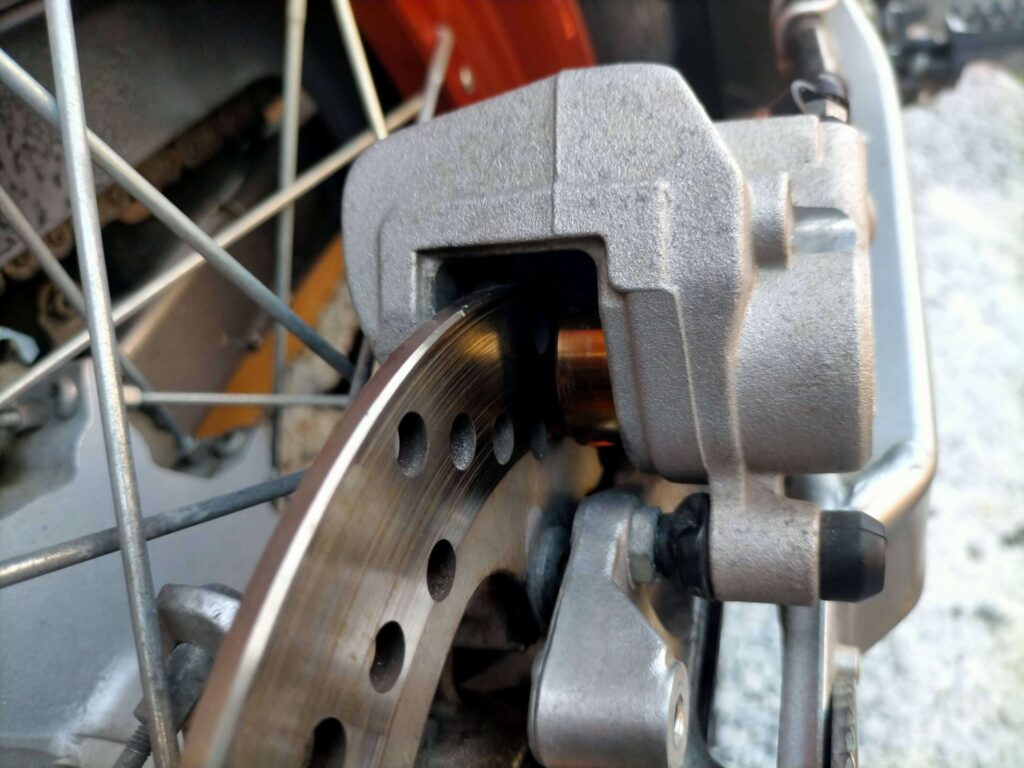 セロー250リヤブレーキキャリパーのピストンをパーツクリーナーとウエスで清掃している作業