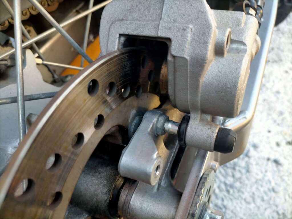 セロー250リヤブレーキキャリパーのゴムブーツをめくってスライドリヤピンにシリコングリスを塗布