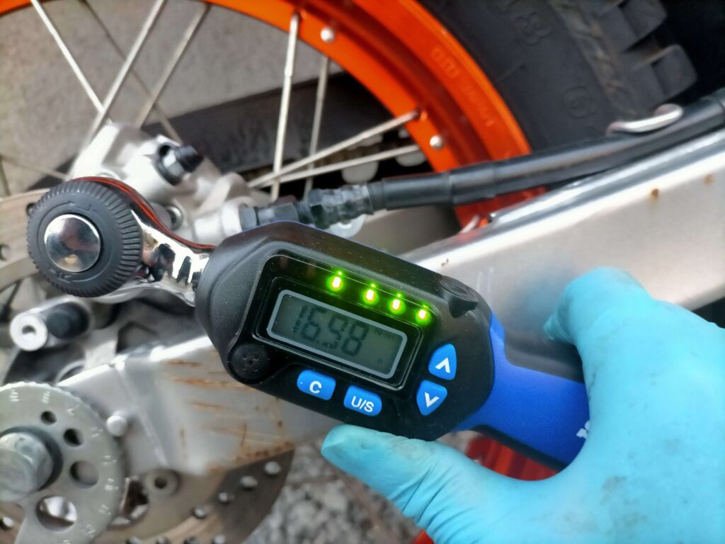 デジタルトルクレンチでセロー250リヤブレーキキャリパーサポートボルトを規定トルク17Nm（1.7kg・m）で締め付けている作業