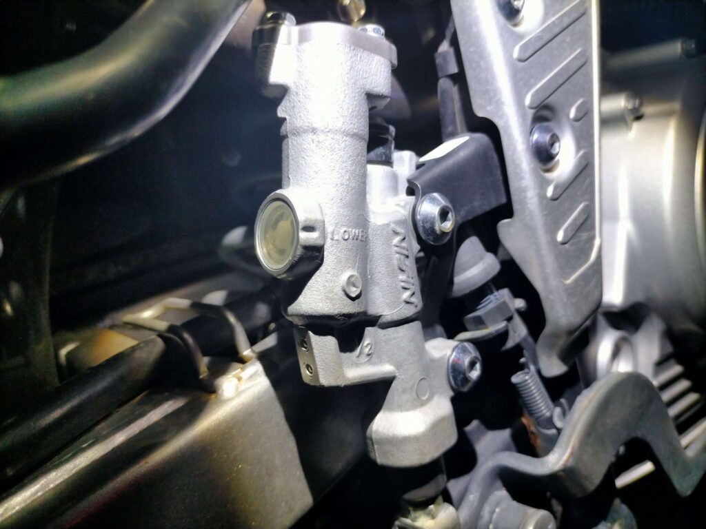 セロー250リヤブレーキのリザーバータンク窓でブレーキフルードのアッパーレベルとロワーレベルを確認している状態