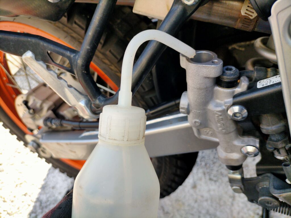 セロー250リヤブレーキのリザーバータンクから古い劣化したブレーキフルードをスポイトで吸い出している作業