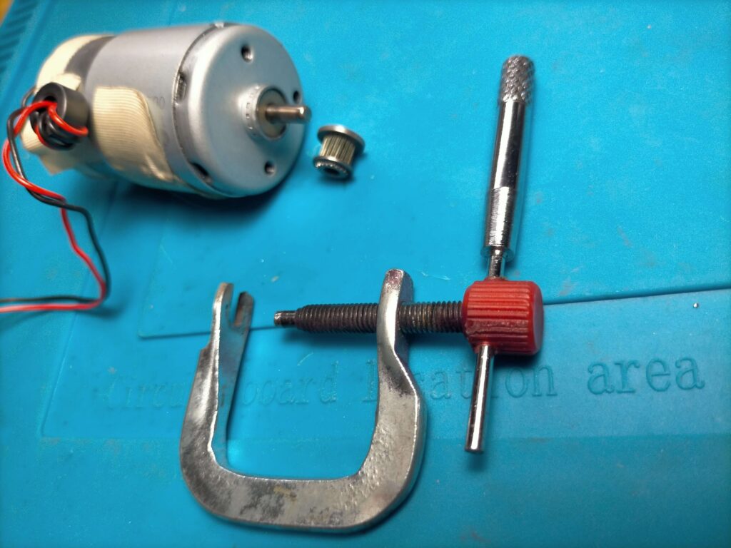 自作ギヤプーラーを使ってプリンター用DCモーター軸からピニオンギヤを取り外している様子