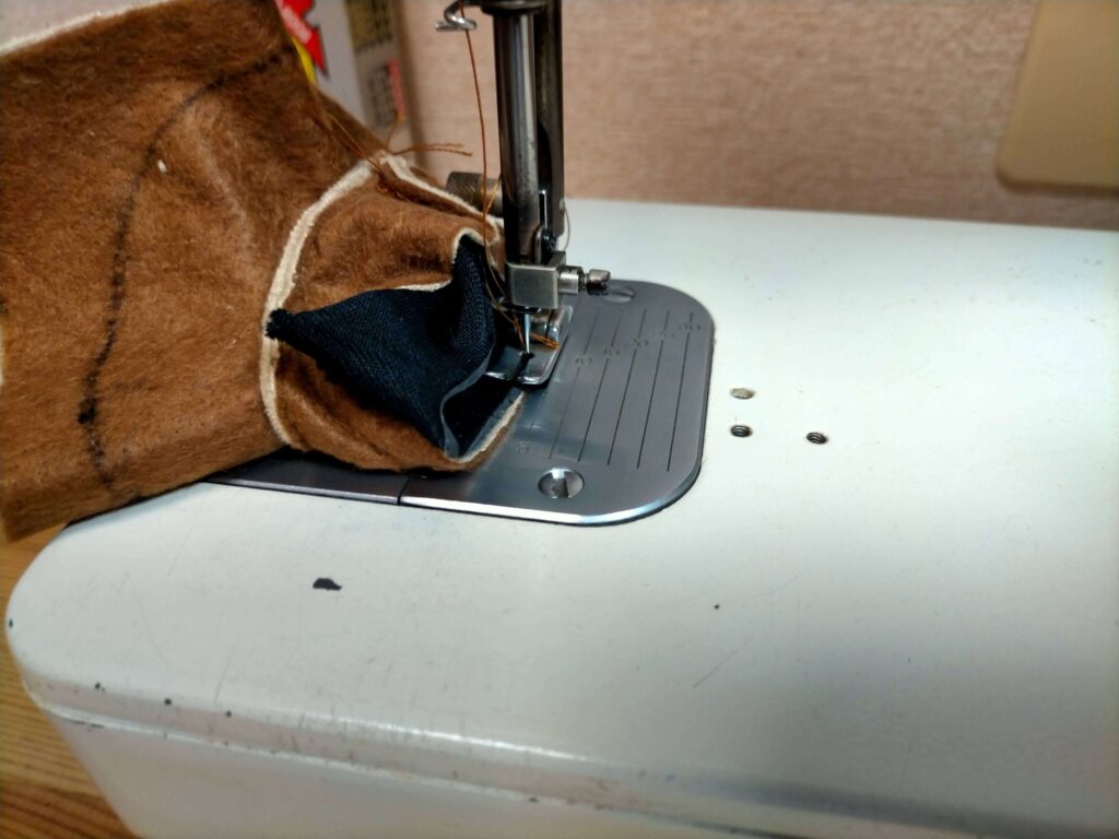 内側面の生地と再利用する黒い裏面パーツをミシンで縫い合わせる工程