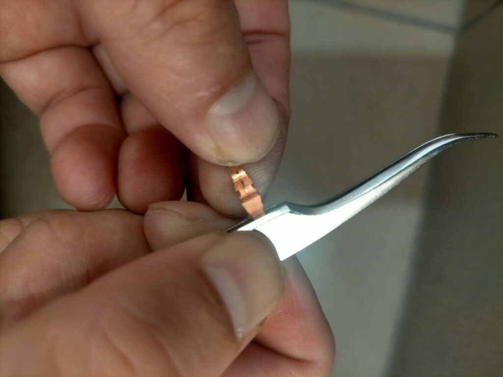 E25キャラバン(いすゞコモ)パワーウィンドウスイッチの接点金具をピンセットで曲げ調整している様子