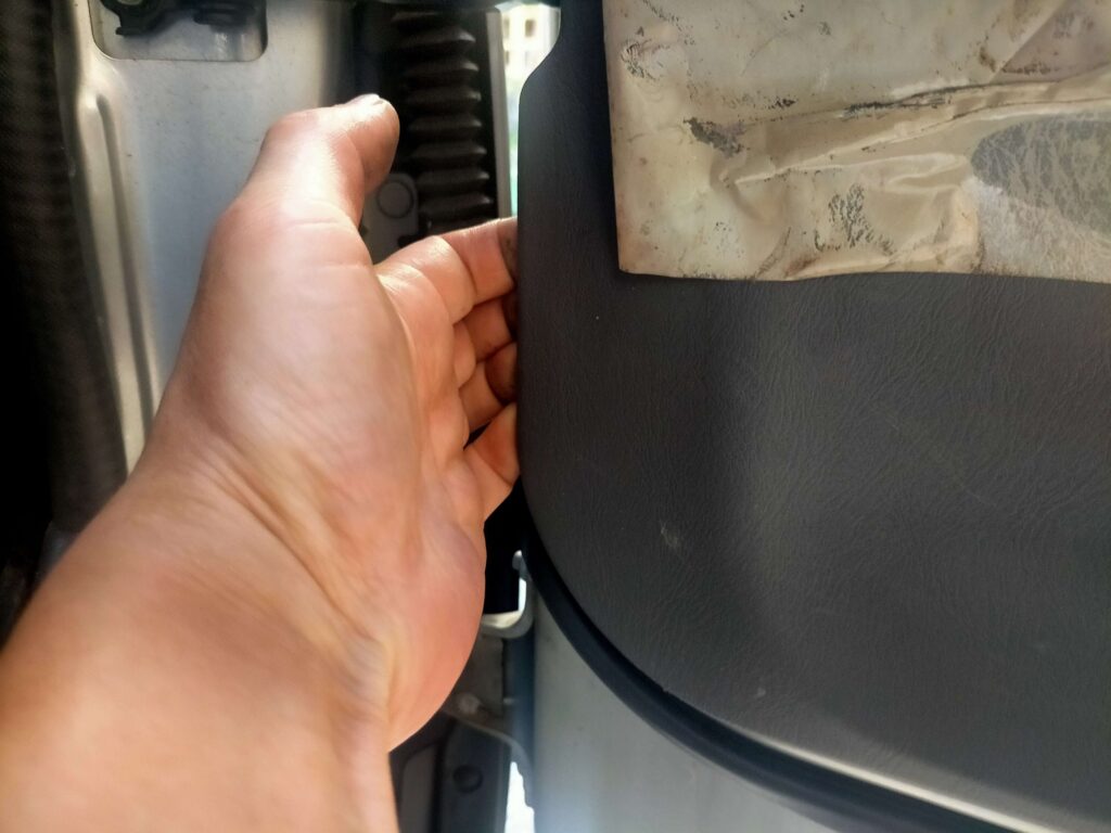 E25キャラバン(いすゞコモ)のドアトリムを手で外している所