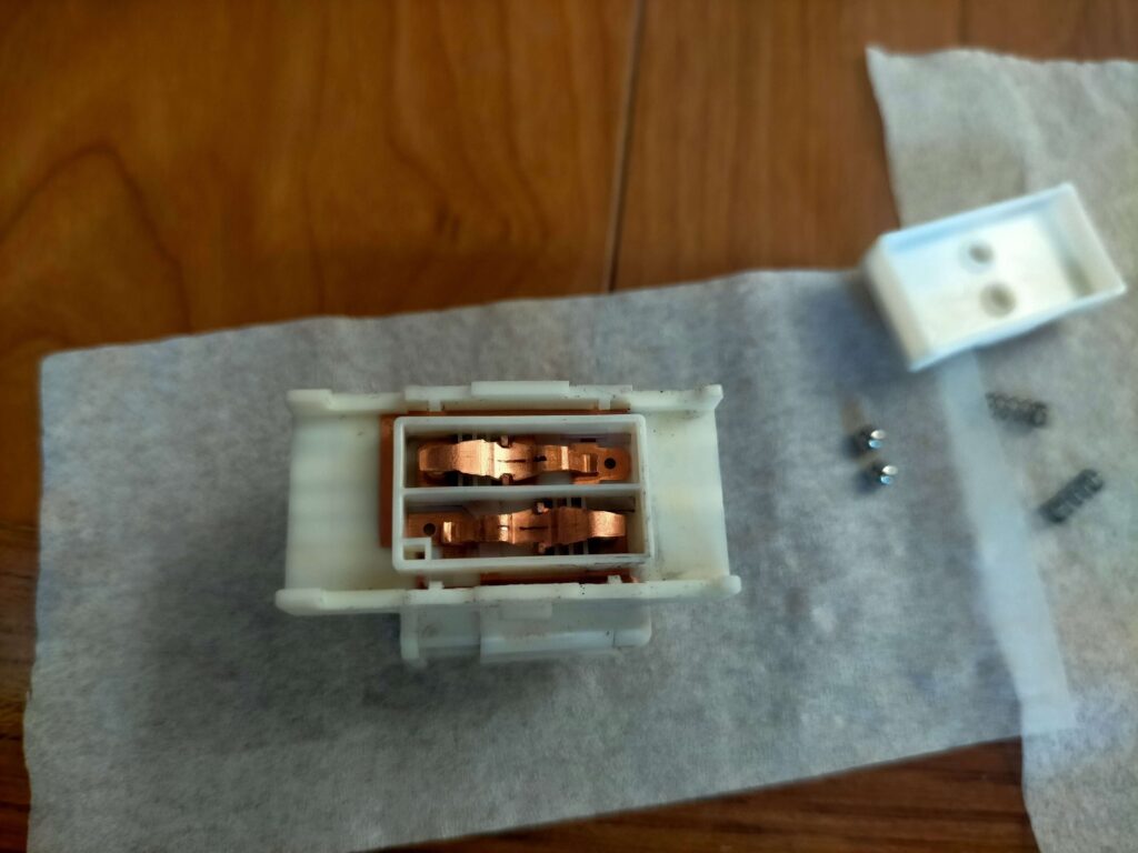 E25キャラバン(いすゞコモ)パワーウィンドウスイッチ清掃後の組み立て作業((接点金具2つを乗せる)