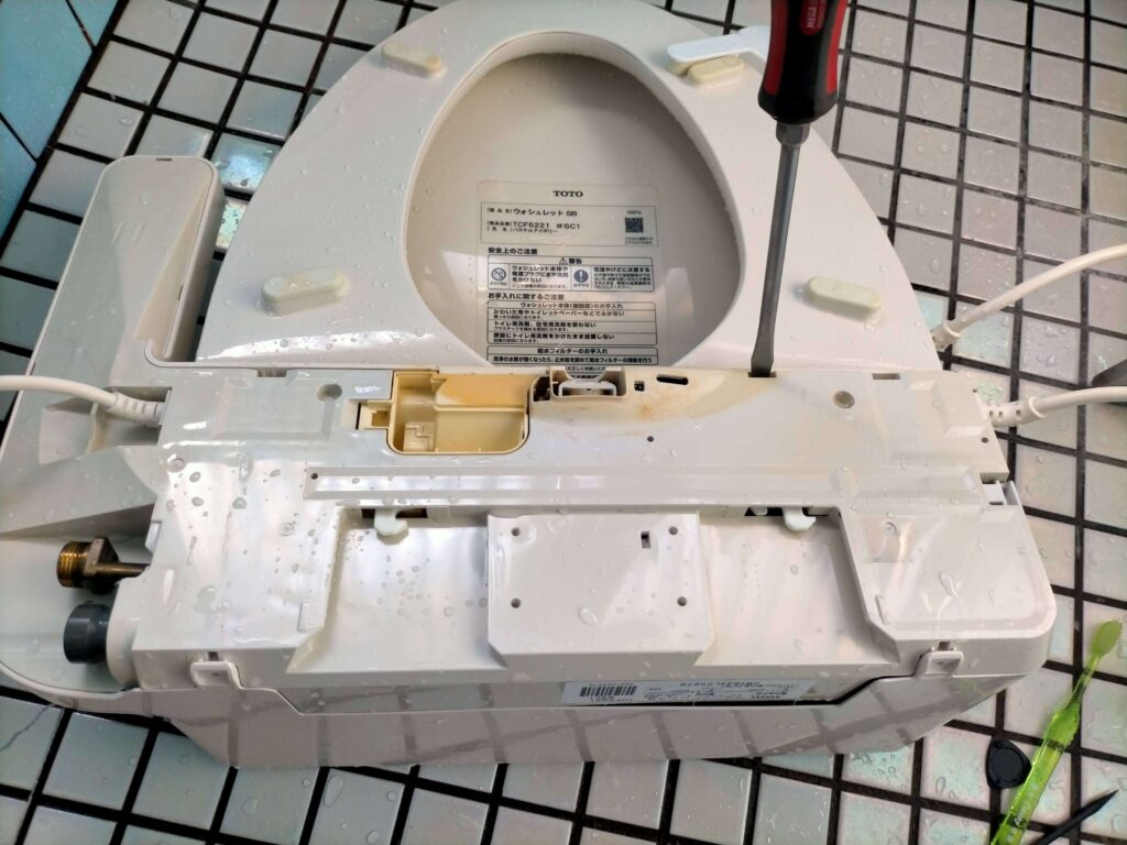 マイナスドライバーでカバーをこじってTOTO ウォシュレット本体を分解
