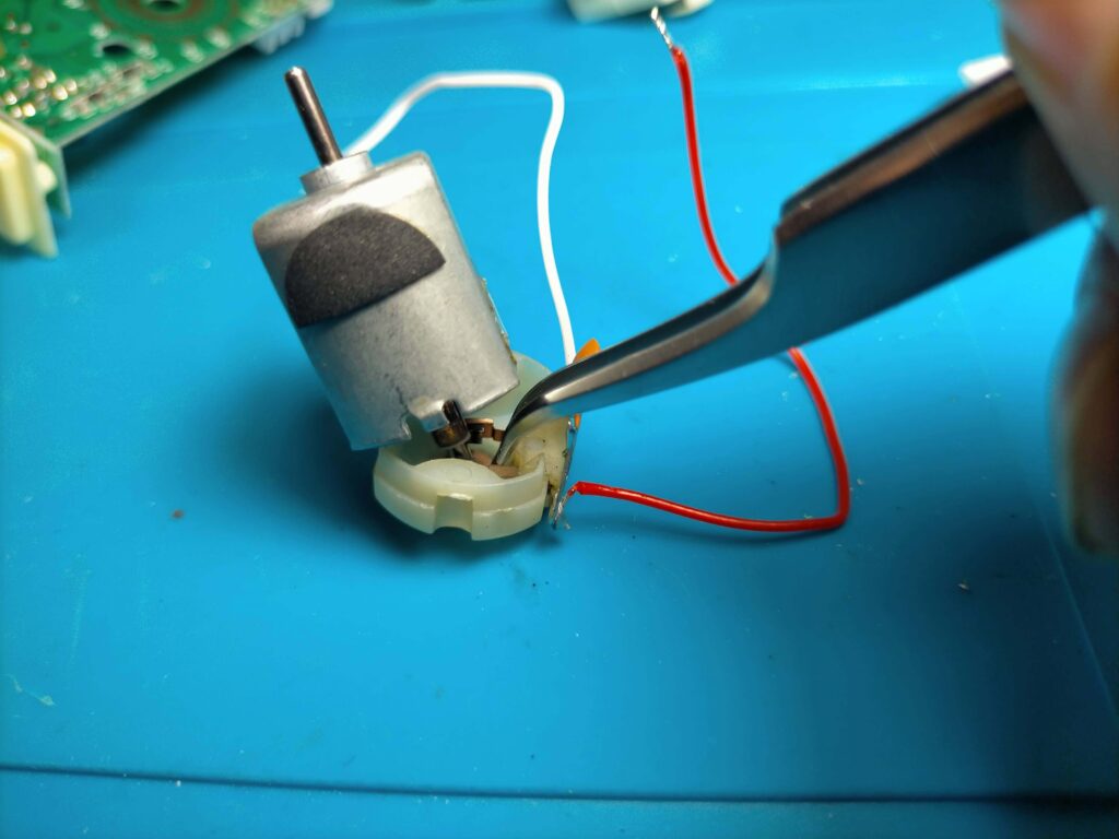 ピンセットで広げたブラシを整流子に挟む作業