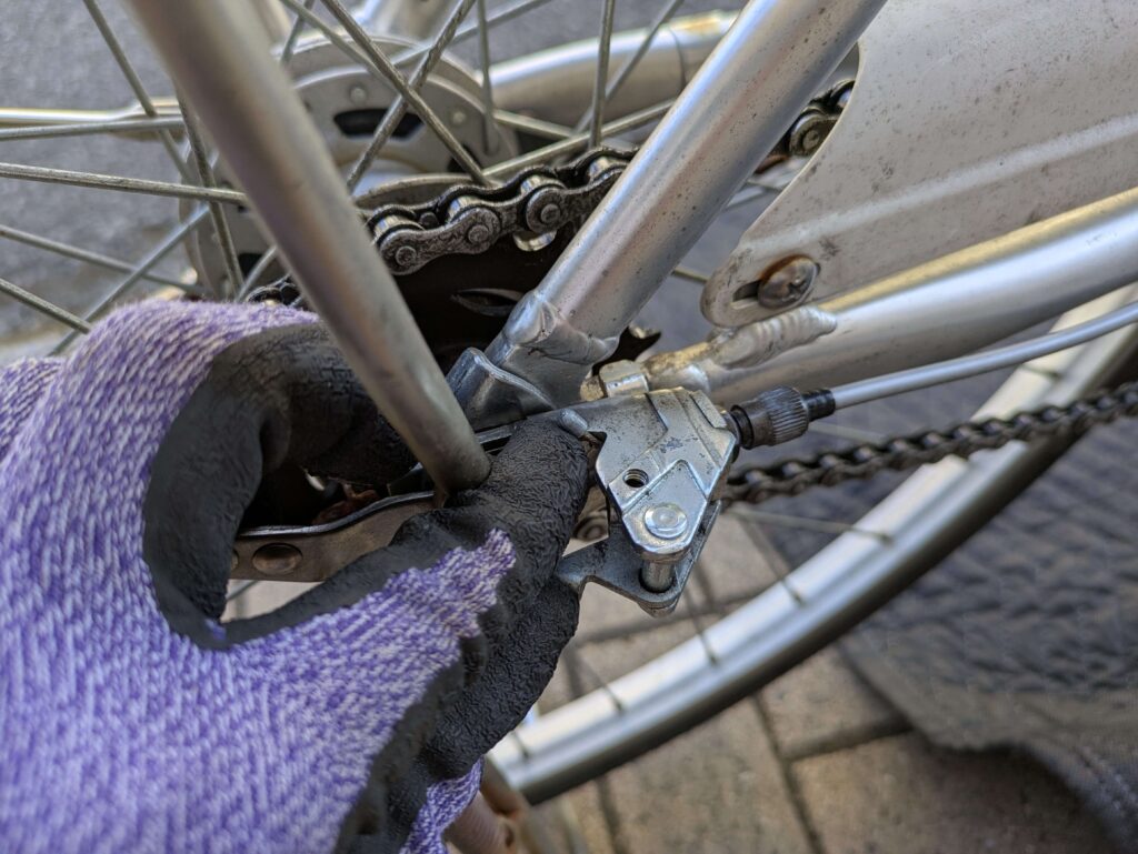 ベルクランクからワイヤー外し（左手人差し指でケーブルエンドキャップを押し上げる）