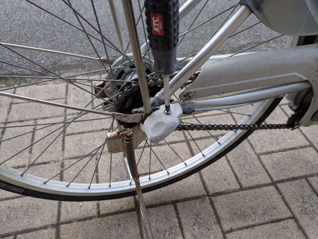 電動自転車後輪のベルクランクカバーをプラスドライバーNo.2で外す作業