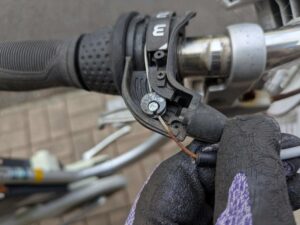 シフトレバーからワイヤーのタイコ（太鼓状金具）を外す作業（1速位置でワイヤー緩む）