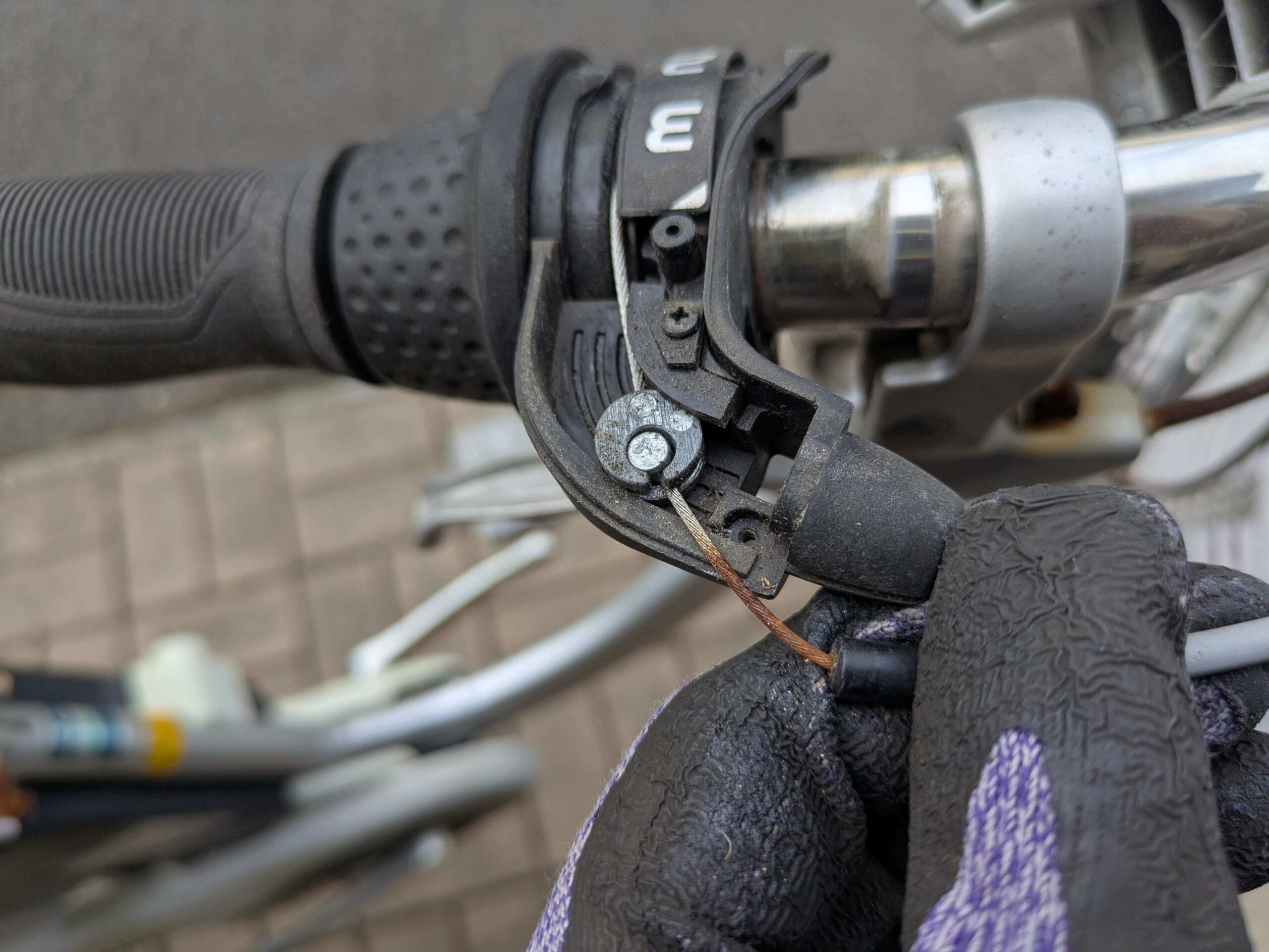 シフトレバーからワイヤーのタイコ（太鼓状金具）を外す作業（1速位置でワイヤー緩む）