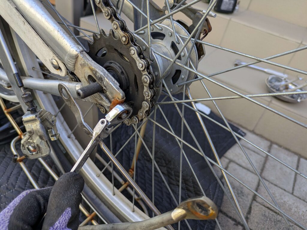 左右のチェーン調整ナット（チェーン引き）を10mmスパナで緩める作業