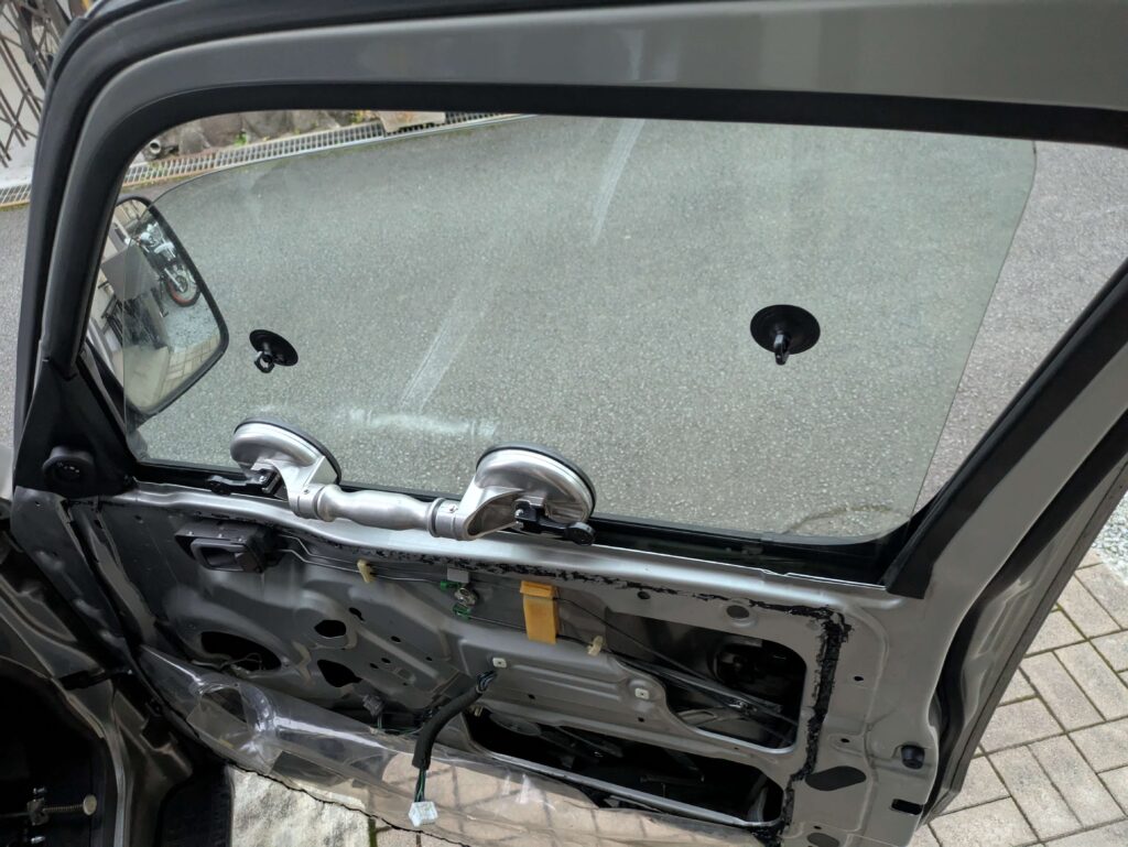 E25キャラバンのドアガラスをバキュームリフター（吸盤）で上に持ち上げて固定した状態