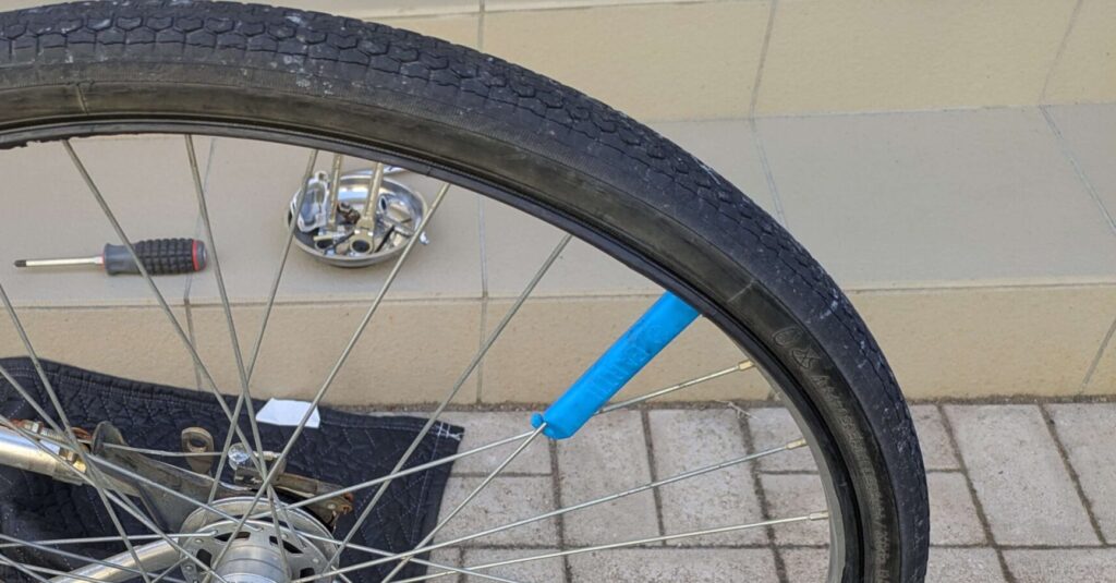 電動自転車の後輪タイヤをタイヤレバーでリムから外す作業