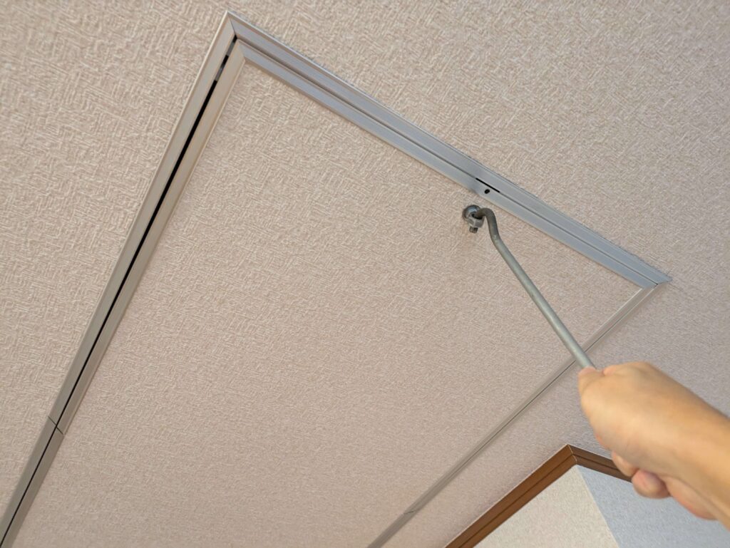 扉のラッチを自作開閉棒で回す作業