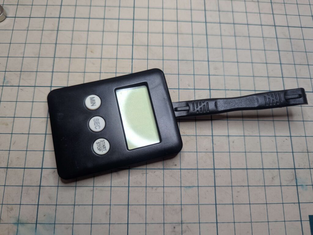 ケースオープナーを使用してキッチンタイマーの裏蓋を慎重に開ける