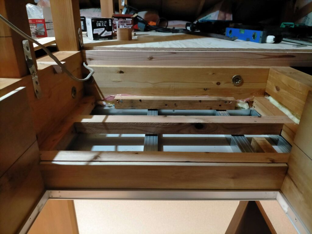 屋根裏収納出入口ステップ下地の根太部にカバー枠をはめ込む作業