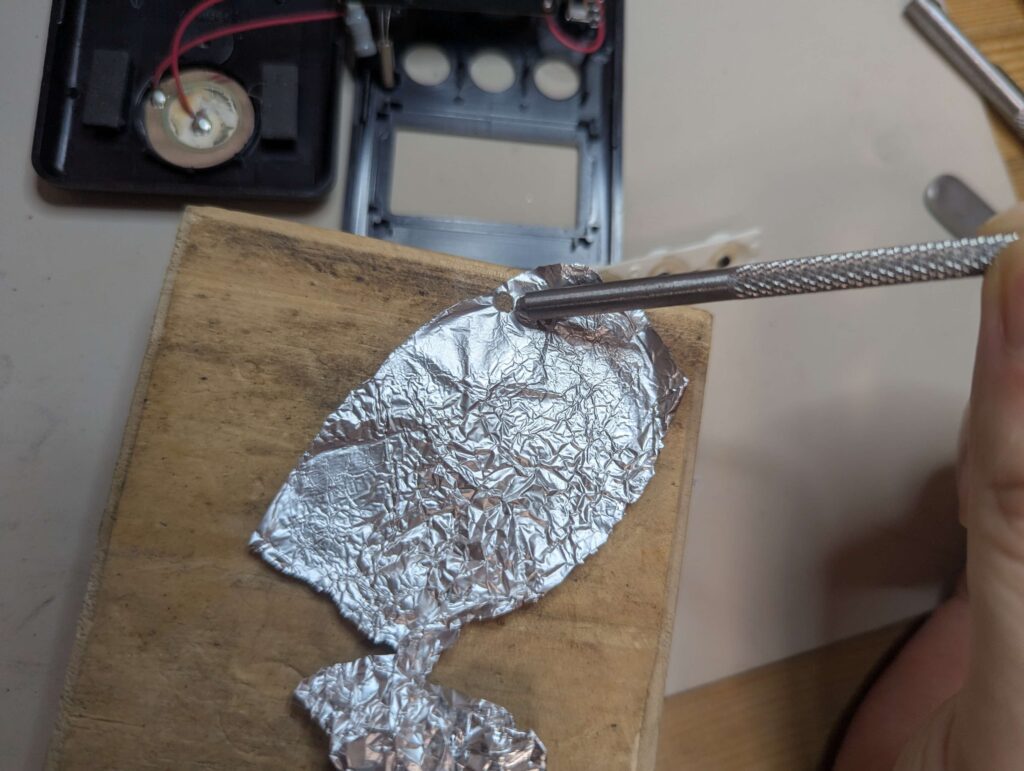 2.5mmの皮抜きポンチを使用してアルミホイルを丸く打ち抜く様子