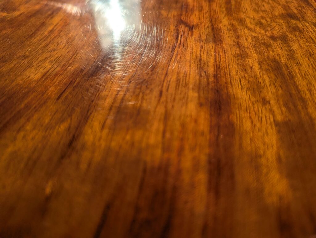 ダイニングテーブルの磨き傷(手磨きで残った無数の傷が太陽光下で見える)