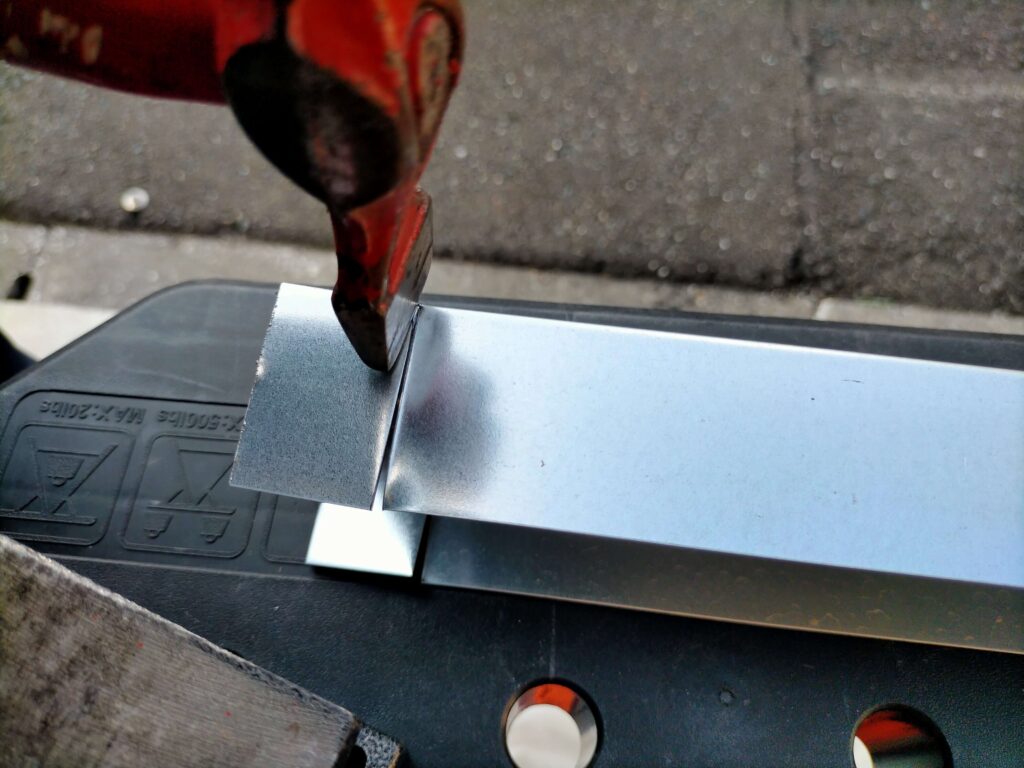 軽天を折り曲げる時に邪魔にならないように耳をハンマーで凹ませている様子