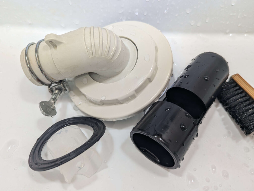 取り外した排水トラップのパーツに付着したヘドロや糸くず汚れを洗い流した様子