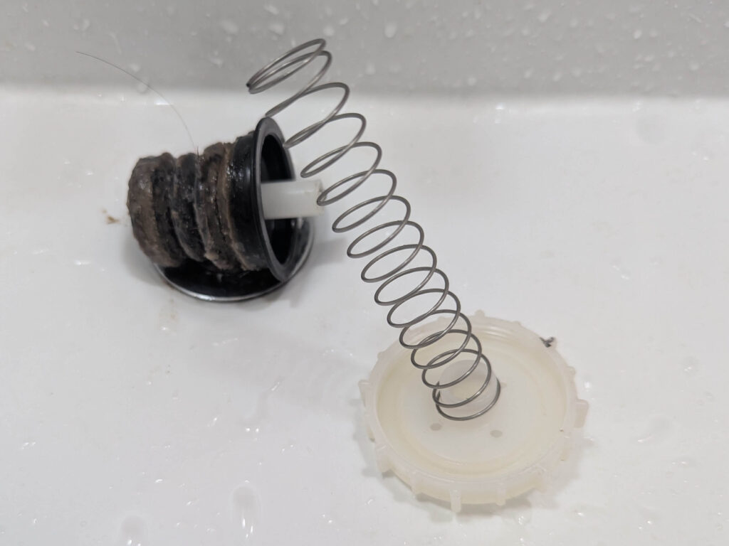 洗濯機から取り外した排水弁パーツ（汚れやヘドロが付着した状態）