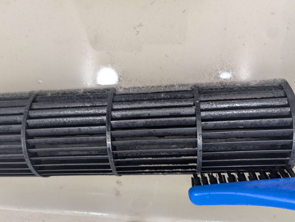 ブラシを使ってシロッコファンのホコリを落としている清掃作業