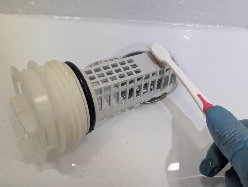 歯ブラシを使って糸くずフィルターの網目の汚れを水洗いする手順