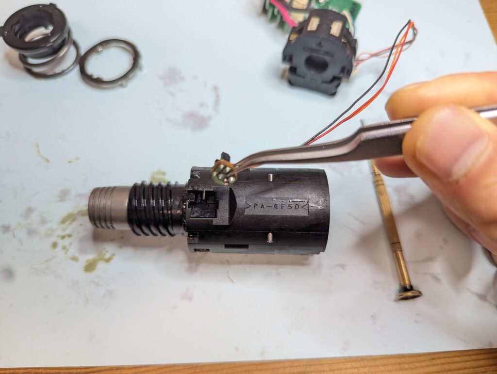 ギアボックス先端のスプリングを外した後、オートストップ機能用のフォトセンサー部品を分離する様子