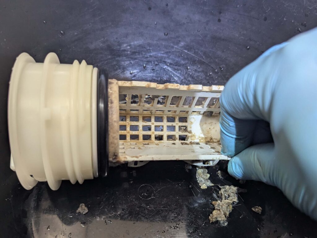 糸くずフィルターのネットに溜まったゴミや髪の毛を指で取り除く様子